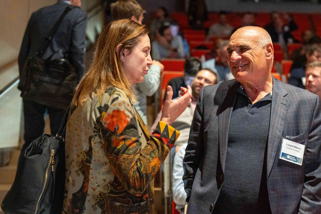 Two attendees in conversation in the auditorium